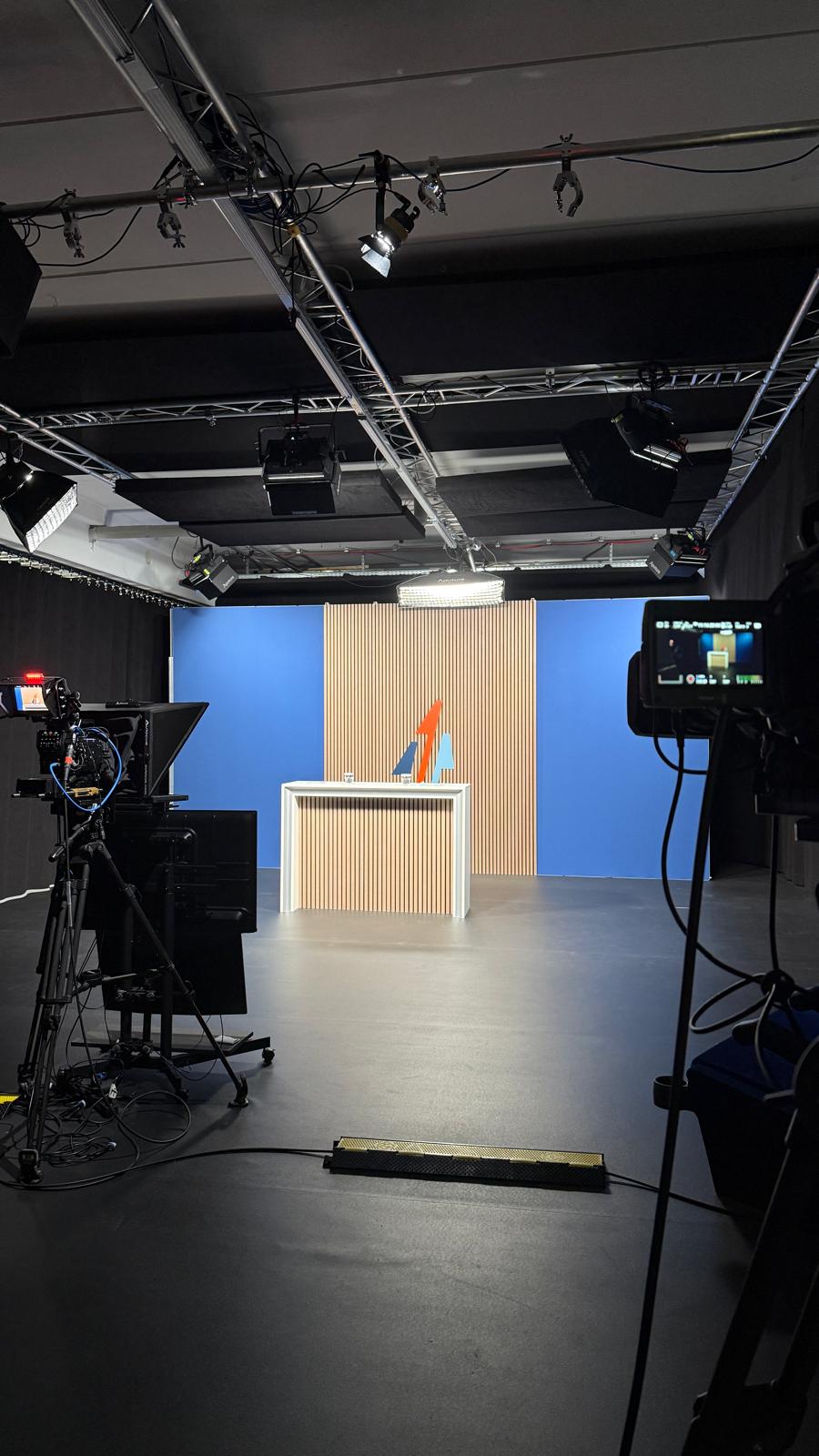 Bühne mit beleuchteter Rückwand und Stehtisch, startklar für die Live-Sendung